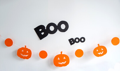 Festive decor on the white wall garland paper in the form of a pumpkin, ghost. Halloween holiday decor.