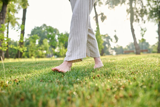 Barefoot woman moving on green lawn