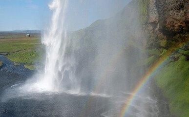 A rainbow in front of Seljalandsfoss waterfall on the southern coast of Iceland on a sunny day