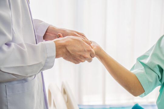 Asian man doctor talks to Asian woman patient in hospital office while  holding the patient hands doing basic medical examination and diagnostic. Healthcare and medical service..