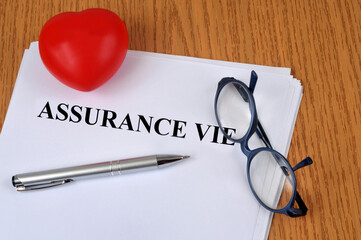 Concept d'assurance vie avec des lunettes, un stylo et un coeur posés sur un contrat en français