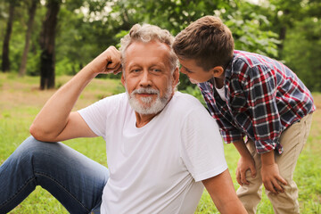 Cute little boy and grandfather spending time together in park