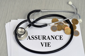 Concept d'assurance vie avec un stéthoscope et de l'argent en cash posés sur un contrat en...