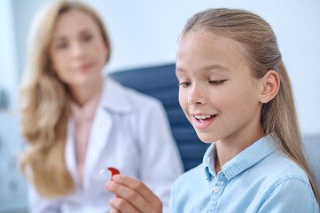 Happy school age girl admiring hearing aid