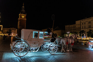 Carriage with horses carrying tourists at night in Krakow, Poland