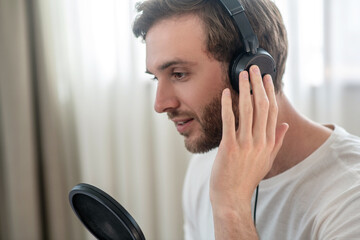 A picture of a man in black headphones speaking in microphone