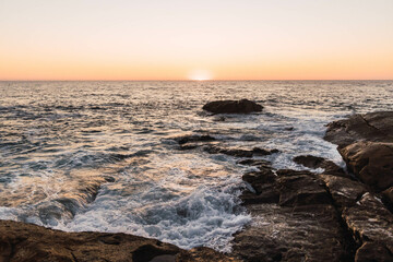 rough sea landscape crashing into rocks at sunset