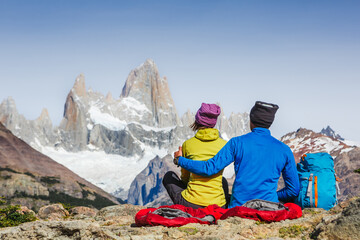 Fototapeta na wymiar Travelers couple in love enjoying the view of majestic Mount Fitz Roy - symbol of Patagonia, Argentina