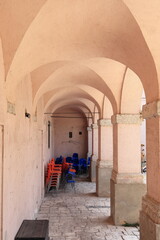 Fototapeta na wymiar Pink Stone Archway with Red and Bue Chairs in Italian Village