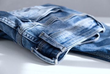 a blue light jeans on a grey background. Close up. Sunlight