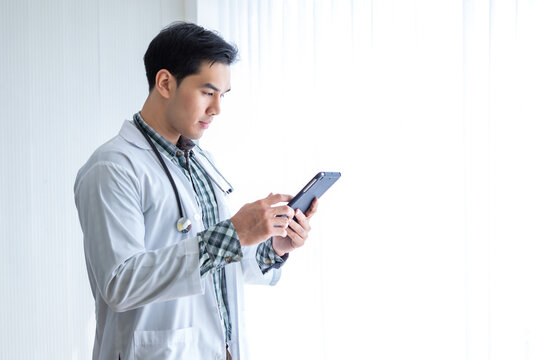 Asian Young Man Doctor Therapeutic Advising With Positive Emotions  Holding Up And Showing Digital Tablet  In Hospital Background,copy Space