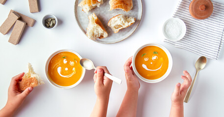 Children eating cream soup with cartoon smiles
