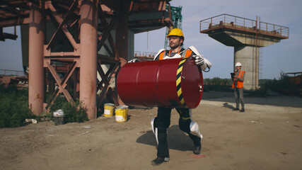 Man in exoskeleton carrying barrel on construction site