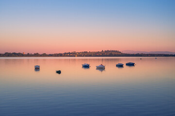 Evening at the lake in Imielin, Silesia, Poland. Little sailboats flowing on the water surface. Mountains silhouette in the background. Beautiful, colorful sky.