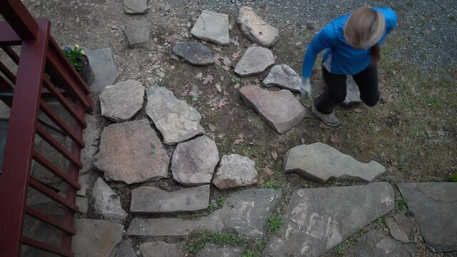 Overhead Shot Of Mature Woman Setting Rocks In Place For Patio Walkway.