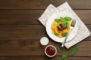Tasty spaghetti squash with tomato sauce and basil served on wooden table, flat lay. Space for text