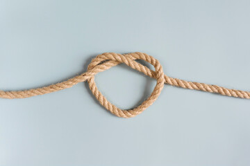 A jute rope tied in the shape of a heart. A symbol of connection, love, a bond. The concept of a strong relationship. A heart-shaped knot.