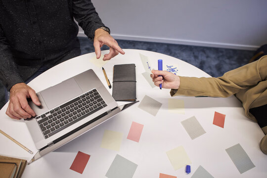 Business people using sticky notes and laptop in office