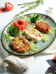 Turkish cuisine. Appetizer in the restaurant. Tartare, vegetable caviar on a green plate on a white table with frieze salad and fresh vegetables. Background image, copy space