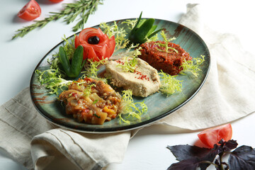 Turkish cuisine. Appetizer in the restaurant. Tartare, vegetable caviar on a green plate on a white table with frieze salad and fresh vegetables. Background image, copy space