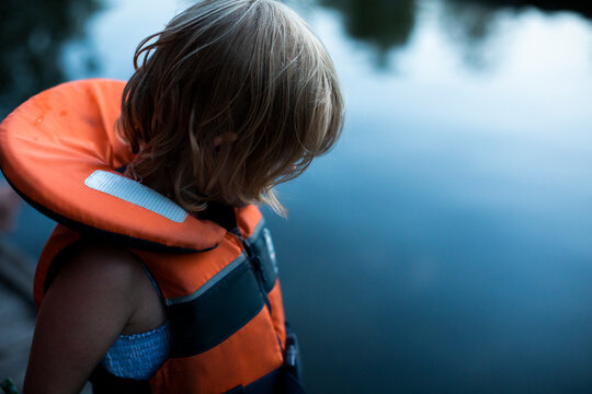 Girl with life jacket at water