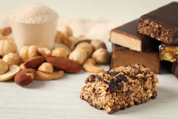 Different tasty protein bars and nuts on white table, closeup
