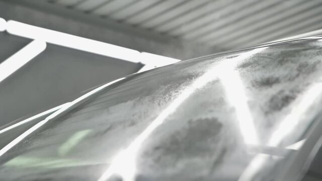 Auto detailing. Polishing black car with machine buffer to polish car in garage. Applying water to the windshield before polishing the car. High quality 4k footage