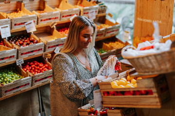 Smiling woman choosing tomatoes in shop