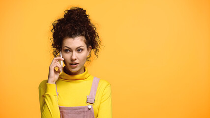 concentrated woman talking on mobile phone isolated on orange