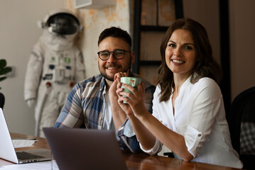 Colleagues in office. Two friends drinking coffee while working in the office.