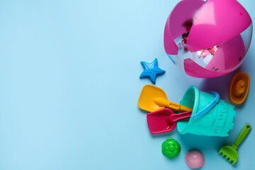 Beach ball and sand toys on light blue background, space for text