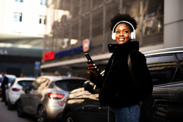 Fototapeta na wymiar Young african woman outdoors. Beautiful woman listening to music while walking through the city.