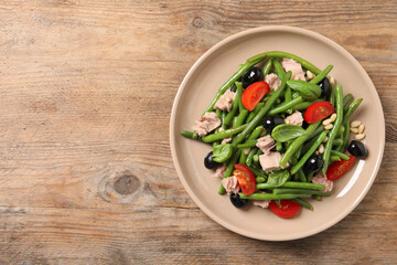 Plate of tasty salad with green beans on wooden table, top view. Space for text