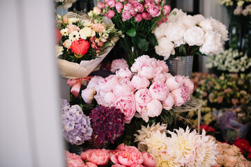 Beautiful fresh blossoming flowers in the florist shop: peonies, dahlias, roses, hydrangea  on the shelve in the florist fridge 