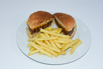 top view of cheeseburger cut in half and french fries served on plate