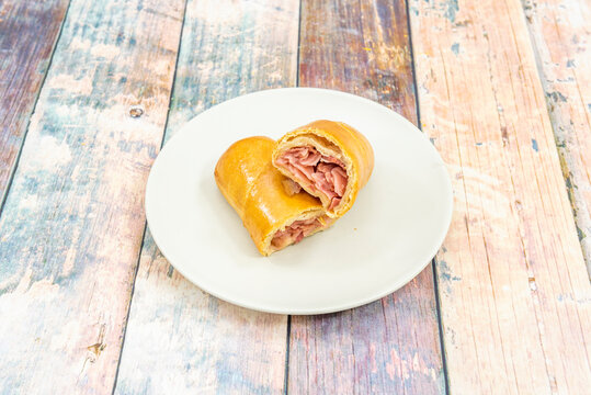 Venezuelan cachito stuffed with ham and cheese on white plate