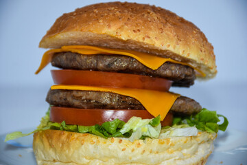 close up of double hamburger with cheddar cheese served on plate