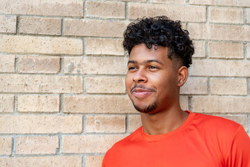 Portrait of young afro latin man against a brick wall