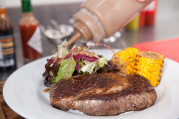 Close up of a delicious beef steak served with salad and sweet corn