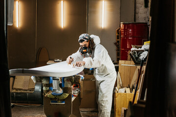 Male with surform tool for shaping surfboard