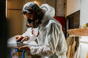 Male shaper using plane on surfboard
