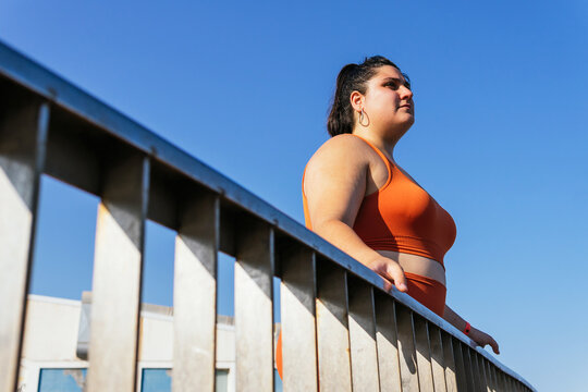 Ethnic sportswoman with excess weight behind fence in sunlight