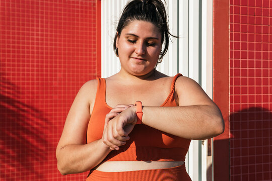 Crop athlete with excess weight checking pulse on smart watch