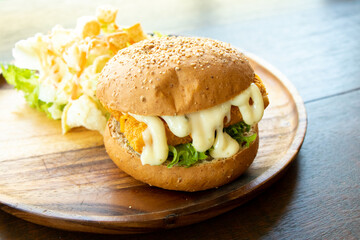 Fried fish fillet burger with vegetable salad on wood plate background