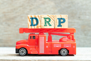Fire ladder truck hold letter block in word DRP on wood background
