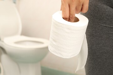 Woman wearing long pants holding toilet paper in the bathroom