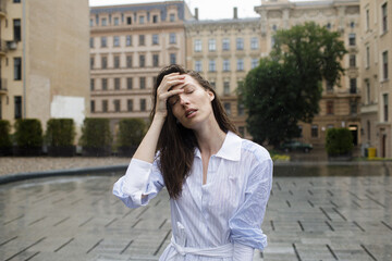 Fototapeta premium Young woman hidden her face in rainy day. Urban city rain. Season fashion for female. Autumn sadness and daily energy. Loneliness and anxiety expression concept. Sad and happy daily life