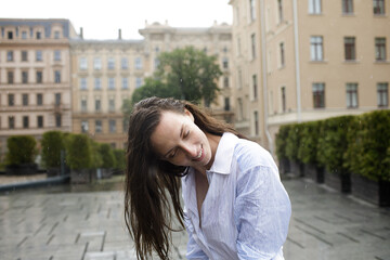 Sentimental woman in the rain. Portrait of a girl. Daily energy in city life. Portrait of female with wet hair and wet dress. Green life at urban environment. Eye closed close up  portrait. Summer joy