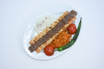 Turkish kebab with bulgur pilaf, roasted tomatoes, roasted peppers, onions and pita bread on plate