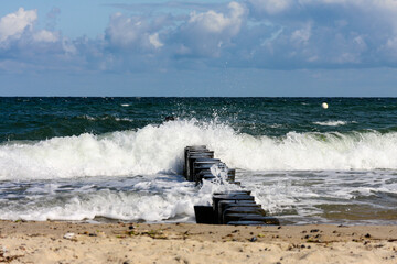 A wave floods a groyne on the Baltic Sea beach 